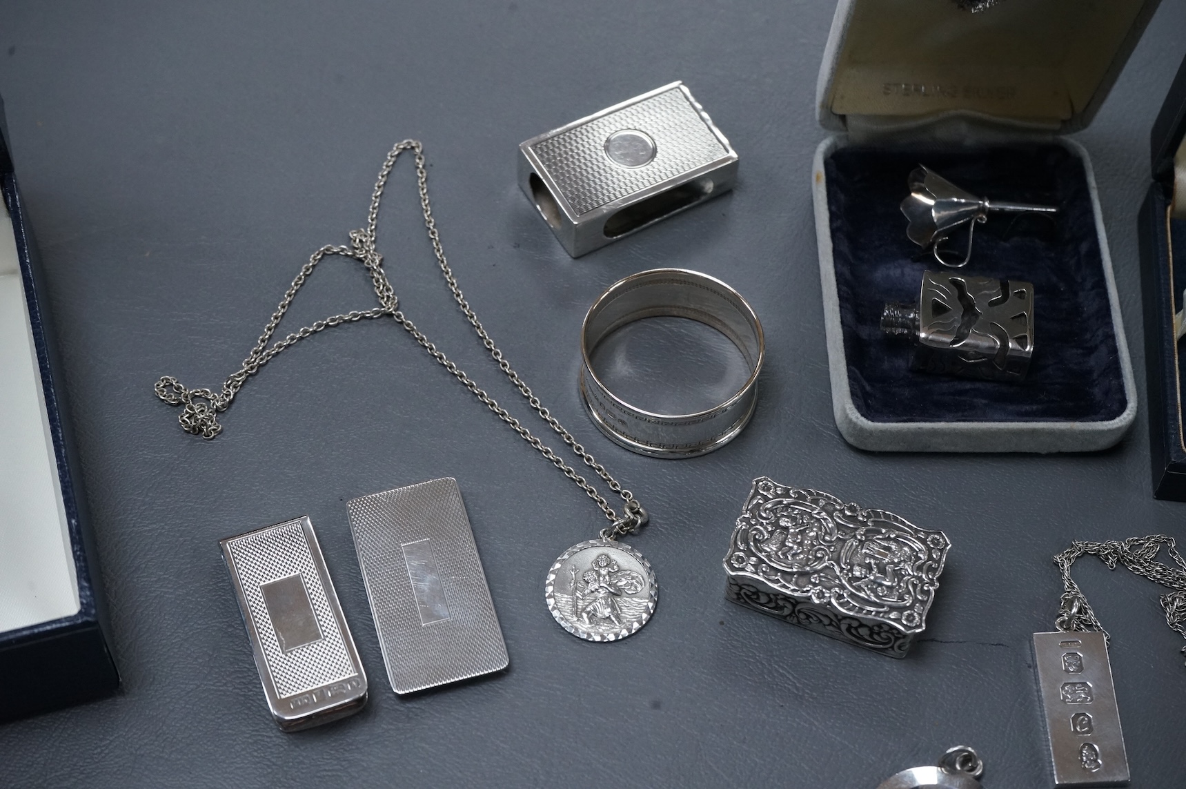 A group of mainly modern silver collectables including three assorted scent flasks and funnels by Ari D. Norman, two money clips, matchbox sleeve, napkin ring, pill box, three pendants including ingot and a pair of Victo